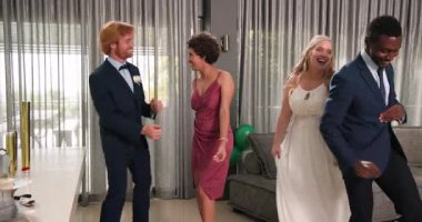 Mutlu gelin ve damat ve çeşitli arkadaşlar oturma odasındaki düğün resepsiyonunda konfeti atıyorlar. Kutlama, düğün, ilişki, parti ve arkadaşlık kavramı.