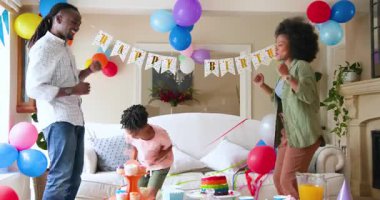 Mutlu siyah çift ve onların çok ırklı oğulları dans ediyor ve gülümsüyor, çocuğun doğum gününü evde kutluyorlar. Doğum günü, kutlama, parti, aile, çocukluk, ev hayatı ve ilişki kavramı.