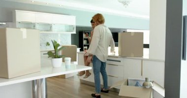 Happy ve çift tezgahın yanında oturuyorlar, akıllı telefon kullanıyorlar ve mutfakta konuşuyorlar. Taşınmak, konut ve ev hayatı kavramı.