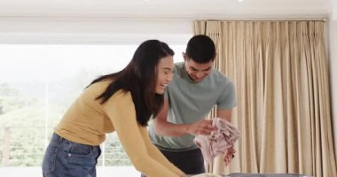 Asyalı çift evde bavul hazırlıyor, heyecanla tatile hazırlanıyorlar. Seyahat, turizm, boş zaman, macera, bagaj