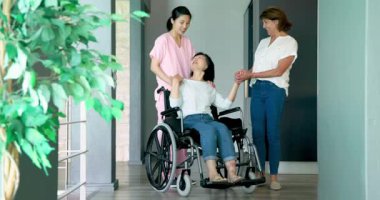 Bayan hemşire ve arkadaşıyla birlikte tekerlekli sandalyede oturan mutlu son sınıf öğrencisi. Kıdemli yaşam tarzı, sakatlık, sağlık ve arkadaşlık konsepti.