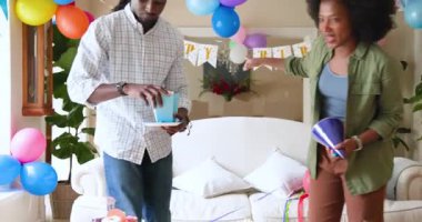 Mutlu siyah çift ve çok ırklı oğlu, çocuğun doğum gününü evde kutladıktan sonra oturma odasını temizliyor. Doğum günü, kutlama, parti, aile, çocukluk, ev hayatı ve ilişki kavramı.