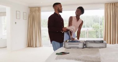 Afro-Amerikalı çift bavullarını yatak odasına topluyor, birlikte tatile hazırlanıyorlar. Seyahat, turizm, bagaj, kaçış, tatil, hazırlık