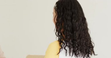 Çeşitli kadın aile yatak odasındaki kutuyu açıyor, seyahat için mor battaniyeyi gümüş bavula dolduruyorlar. Aile, ambalaj, organizasyon, yerli, işbirliği, yaşam tarzı, minimalist