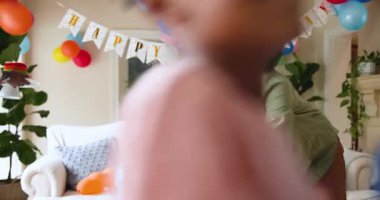 Mutlu siyah çift ve çok ırklı oğlu, çocuğun doğum gününü evde kutladıktan sonra oturma odasını temizliyor. Doğum günü, kutlama, parti, aile, çocukluk, ev hayatı ve ilişki kavramı.