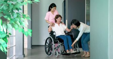 Tekerlekli sandalyede oturan, bayan hemşire kız arkadaşıyla koridorda konuşan mutlu kıdemli kadın. Kıdemli yaşam tarzı, sakatlık, sağlık ve arkadaşlık konsepti.