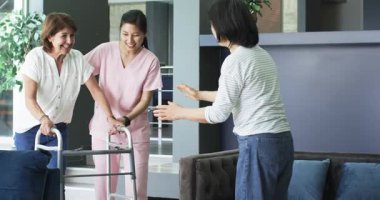 Oturma odasında konuşan hemşire ve bayan arkadaşıyla yürüyen çerçeveyi kullanan mutlu bir son sınıf kadını. üst düzey yaşam tarzı, engellilik, sağlık ve arkadaşlık konsepti.