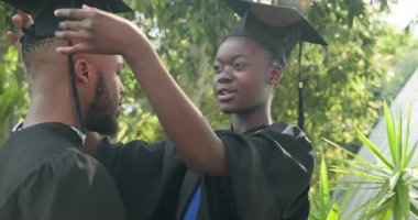 Mezuniyeti kutlayan, gecelikli Afro-Amerikan çift dışarıda neşeli hissediyorlar. Kutlama, akademik başarı, başarı, tören, mutluluk