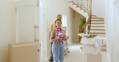 Mutlu siyah kadın ve elinde içki tutan adam, karton kutular taşıyan adam, güneşli bir günde yeni bir eve taşınıyor. Yeni ev, mülk, mutluluk, yaşam tarzı ve ilişki kavramı.