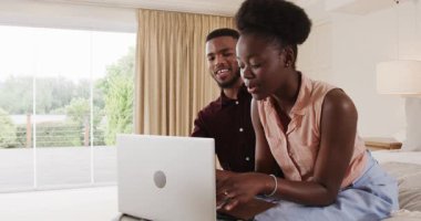 Evde dizüstü bilgisayardan bir şey izlerken birlikte gülen Afro-Amerikalı çift. çeşitlilik, dijital, teknoloji, mutluluk, bağ, bağlantı