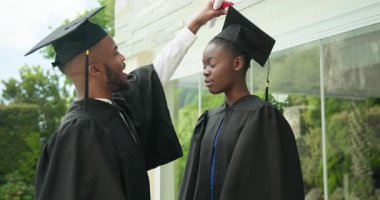 Kep ve cübbe ile mezun olan öğrenciler, açık havada başarıyı birlikte kutluyorlar. Mezuniyet, tören, kutlama, başarı, eğitim, akademik