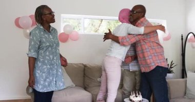 Pasta mumlarına tepki veren pembe başörtülü son sınıf beyaz kadın ve kanepedeki son sınıf arkadaşlarını selamlıyor. Arkadaşlık, kutlama, arkadaşlık, destek, sıcaklık, birliktelik, neşe