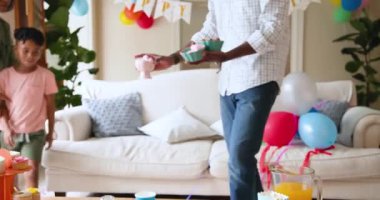 Mutlu siyah çift ve çok ırklı oğlu, çocuğun doğum gününü evde kutladıktan sonra oturma odasını temizliyor. Doğum günü, kutlama, parti, aile, çocukluk, ev hayatı ve ilişki kavramı.