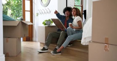 Mutlu çift konuşuyor, sarılıyor ve kahve içiyor. Yeni evin koridorunda kutularla oturuyorlar. eve taşınma, ilişki, yaşam tarzı ve mülkiyet kavramı.