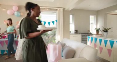 Bebekleri olan, çok ırklı, beyaz ve siyah bir grup arkadaş güneşli oturma odasındaki bir bebek partisinde temizlik ve sohbet yapıyorlar. Kutlama, annelik, parti, yaz ve arkadaşlık kavramı.