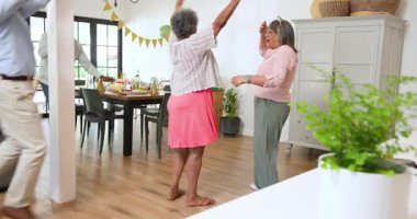 Bir grup mutlu üst düzey çok ırklı, beyaz ve siyah erkek ve kadın arkadaş oturma odasındaki bir doğum günü partisinde kutlama yapıyorlar. Kutlama, doğum günü, parti, son sınıf yaşam tarzı ve arkadaşlık konsepti.