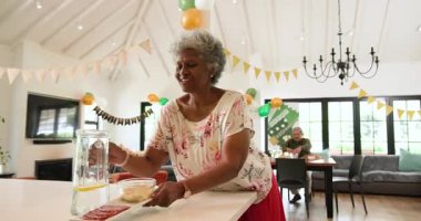Oturma odasındaki emeklilik partisinde çok ırklı, beyaz ve siyah erkek ve kadın arkadaşlardan oluşan mutlu bir grup. Kutlama, emeklilik, parti, son sınıf yaşam tarzı ve arkadaşlık kavramı.