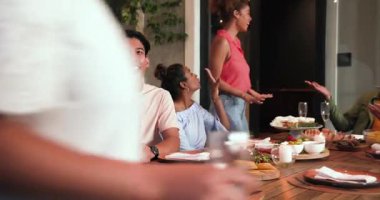 Masanın etrafında toplanmış, bir kutlama partisinde konuşan ve kadeh kaldıran mutlu arkadaşlar. Kutlama, akşam yemeği, yaşam tarzı ve arkadaşlık konsepti..