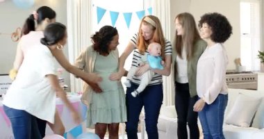 Bir grup mutlu, çok ırklı ve beyaz, bebek kucaklayan ve güneşli oturma odasındaki bir bebek partisinde konuşan bayan arkadaş. Kutlama, annelik, parti, yaz ve arkadaşlık kavramı.