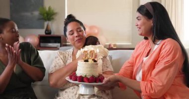 Doğum günü pastasında mum üfleyerek doğum günü partisi veren üç mutlu, çok ırklı ve zenci bayan arkadaş. Kutlama, doğum günü, parti, yaz ve arkadaşlık kavramı.