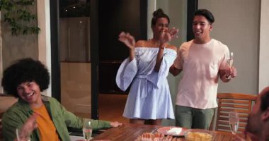 Ayakta duran, tost içen, kucaklaşan, masada oturan arkadaşlarıyla kutlama yapan mutlu çift. Kutlama, akşam yemeği, yaşam tarzı ve arkadaşlık konsepti.