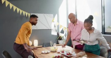 Bir grup mutlu çok ırklı ve siyah erkek ve kadın arkadaş oturma odasındaki bir doğum günü partisinde masayı temizliyor. Kutlama, doğum günü, parti, yaz ve arkadaşlık kavramı.