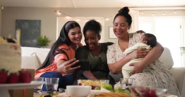 Üç tane mutlu, çok ırklı, siyah ve bebekli bayan arkadaş oturma odasındaki bir doğum günü partisinde fotoğraf çekiyorlar. Kutlama, doğum günü, parti, yaz ve arkadaşlık kavramı.