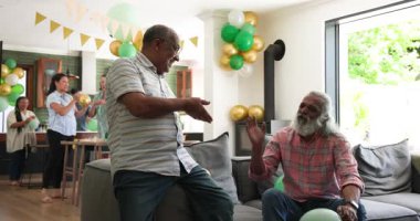 Mutlu kıdemli arkadaşlar konuşuyor, balonları şişiriyor ve parti için evi dekore ediyor. Hazırlık, kutlama, birliktelik, kıdemli yaşam tarzı ve arkadaşlık kavramı.