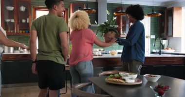 Şarap ve çiçeklerle gelen ve mutfakta kucaklaşan farklı çiftler. Kutlama, parti, birliktelik, yaşam tarzı ve arkadaşlık kavramı.