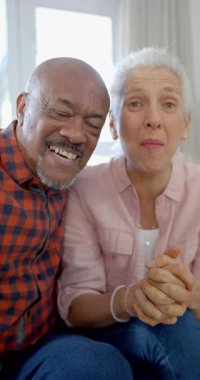 Mutlu yaşlı çift portresinin dikey videosu. Yavaş çekimde evde video görüşmesi yapıyorlar. Ev hayatı, emeklilik, teknoloji ve yaşam tarzı, değişmedi..