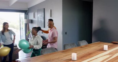 Bir grup mutlu çok ırklı ve siyah erkek ve kadın arkadaş oturma odasındaki bir doğum günü partisinde süslemeleri temizleyip kucaklaşıyorlar. Kutlama, doğum günü, parti, yaz ve arkadaşlık kavramı.