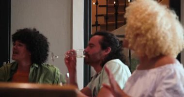 Masanın etrafında toplanmış, kadeh kaldıran ve bir kutlama partisinde kucaklaşan mutlu arkadaşlar. Kutlama, akşam yemeği, yaşam tarzı ve arkadaşlık konsepti..