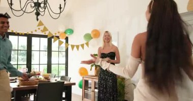 Bir grup mutlu, çok ırklı, beyaz ve Hintli erkek ve kadın arkadaş güneşli oturma odasında sarılıp kutluyorlar. Kutlama, doğum günü, parti, yaz ve arkadaşlık kavramı.