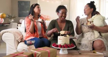 Doğum günü pastası yiyen üç mutlu, çok ırklı ve siyah bayan arkadaş oturma odasında. Kutlama, doğum günü, parti, yaz ve arkadaşlık kavramı.