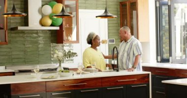 Mutfakta balonlarla süslenmiş temizlik ve dans yapan mutlu kıdemli çift. Yaşlılık, ev hayatı, aşk, mutluluk, yaşam tarzı ve ilişki konsepti.