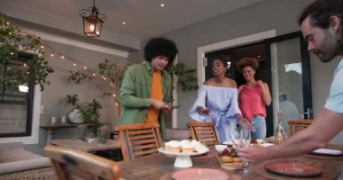 Evde akşam yemeği partisi için yemek ve içeceklerle sofrayı hazırlayan çeşitli arkadaşlarınız kutlu olsun. Kutlama, akşam yemeği, birliktelik, yaşam tarzı ve arkadaşlık konsepti..