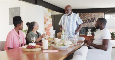 Mutlu siyah çift ve yaşlı aile oturma odasındaki emeklilik partisinde kadeh kaldırıyor. Kutlama, emeklilik, parti, son sınıf yaşam tarzı ve aile kavramı.