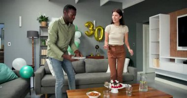 Mutlu çok ırklı ve Afro-Amerikalı çift oturma odasındaki bir doğum günü partisinde masadan bulaşıkları yıkıyor. Kutlama, doğum günü, parti ve yaşam tarzı konsepti.