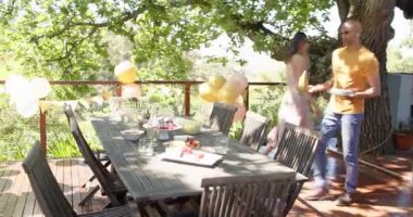 Bir grup mutlu çok ırklı ve siyah erkek ve kadın arkadaş güneşli bir günde bahçede bir doğum günü partisi için hazırlanıyorlar. Kutlama, doğum günü, parti, yaz ve arkadaşlık kavramı.