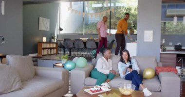 Bir grup mutlu çok ırklı ve siyah erkek ve kadın arkadaş oturma odasında bir doğum günü partisi için dekorasyon hazırlıyorlar. Kutlama, doğum günü, parti, yaz ve arkadaşlık kavramı.