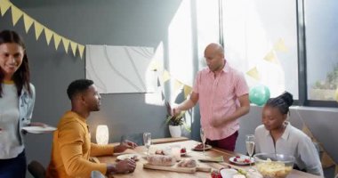 Bir grup mutlu çok ırklı ve siyah erkek ve kadın arkadaş oturma odasındaki bir doğum günü partisinde masayı temizliyor. Kutlama, doğum günü, parti, yaz ve arkadaşlık kavramı.