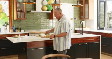 Mutlu kıdemli çift konuşuyor ve güneşli bir günde balonlarla süslenmiş mutfağı temizliyor. Yaşlılık, ev hayatı, aşk, mutluluk, yaşam tarzı ve ilişki konsepti.