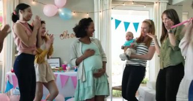 Bir grup mutlu, çok ırklı ve beyaz, bebek kucaklayan ve güneşli oturma odasındaki bir bebek partisinde konuşan bayan arkadaş. Kutlama, annelik, parti, yaz ve arkadaşlık kavramı.