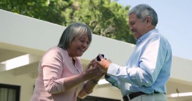 Mutlu kıdemli çok ırklı ve beyaz çift güneşli bir günde terasta evlenme teklif edip kucaklaşıyorlar. Kutlama, nişan ve yaşlılar yaşam tarzı konsepti.