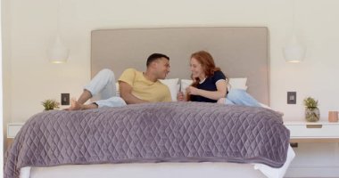 Bebek haberlerini paylaşan mutlu bir kadın, hamilelik testini erkek arkadaşına gösteriyor ve yatakta sarılıyor. Hamilelik, aile hayatı, aşk, mutluluk, yaşam tarzı ve ilişki kavramı.