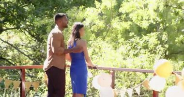 Mutlu çok ırklı ve siyah çift, güneşli bir günde balonlarla terasta evlenme teklif ediyor, kucaklıyor ve kutluyor. Kutlama, nişan, parti, yaz konsepti.