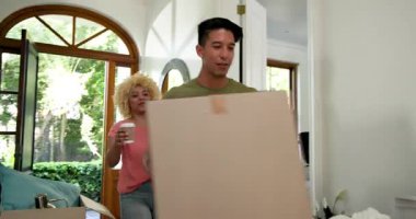 Heyecanlı çeşitli çiftler yeni evlerine kutu taşıyorlar, kucaklaşıyorlar ve salonda kahveyle tost yapıyorlar. eve taşınma, ilişki, yaşam tarzı ve mülkiyet kavramı.