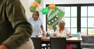 Oturma odasındaki emeklilik partisinde çok ırklı, beyaz ve siyah erkek ve kadın arkadaşlardan oluşan mutlu bir grup. Kutlama, emeklilik, parti, son sınıf yaşam tarzı ve arkadaşlık kavramı.