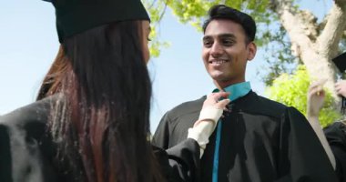 Mezuniyet elbisesi giymiş, güneşli bir günde sarılıp kutlama yapan mutlu, çok ırklı, beyaz ve Hintli erkek ve kadın arkadaşlar grubu. Kutlama, mezuniyet, eğitim ve arkadaşlık kavramı.