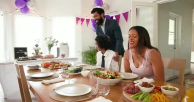 Çeşitli aileler geleneksel törenleri kutluyor, masada oturuyor, yemek yiyor ve evde sarılıyorlar. Bar mitzvah, bat mitzvah, Aile, ebeveynlik, gelenek ve kutlama konsepti.